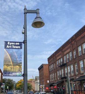 A view of Spring Street in downtown Williamstown. From the light post hangs a banner showing a rainbow photograph by artist Carol Stegeman.