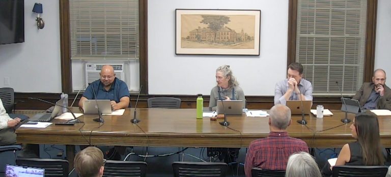 people sitting around a table at a select board meeting