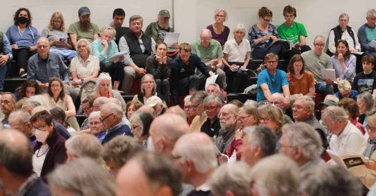 people sitting together in a gym at Town Meeting