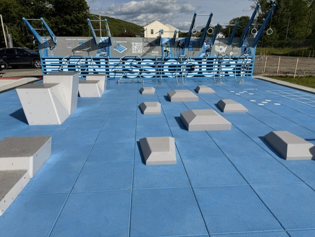 photo of the fitness court  - blue pad with light grey exercise features.